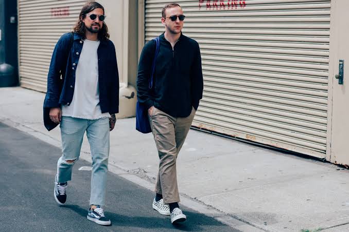 Dua pria sedang berjalan dengan style casual dan menggunakan sepatu Vans